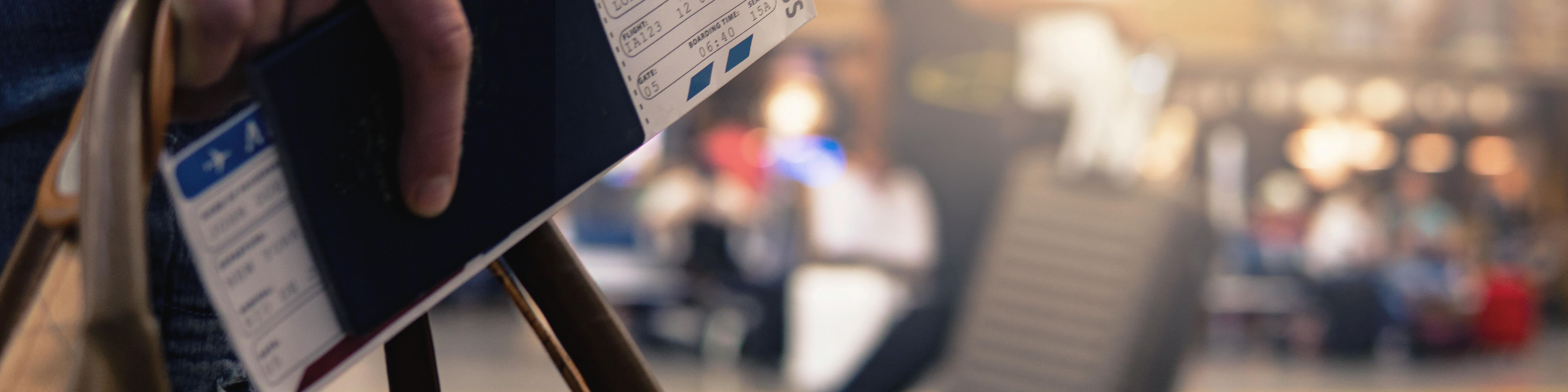 A man carrying a bag, holding his passport and airplane ticket at an airport.